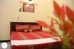 a bedroom with a bed with red sheets and a flower at Sawanga Home Stay in Weligama