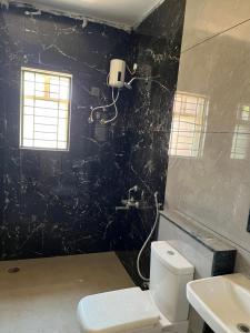 ein Bad mit einem WC und einer schwarzen Wand in der Unterkunft 4C NRI Residency in Tirupati