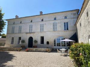 a large stone building with a table and an umbrella at Le Pigeonnier Gite in Verrières