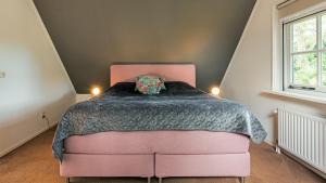 a bedroom with a pink bed with a black comforter at De IJsvogel in Schoorl