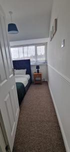 Un pequeño dormitorio con una cama y una mesa. en TLM Stays 3-Bed Entire Home, en Dagenham