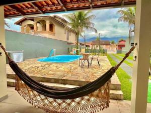 a hammock on a patio next to a pool at Casa com piscina 500m da praia condomínio Morada da Praia in Bertioga
