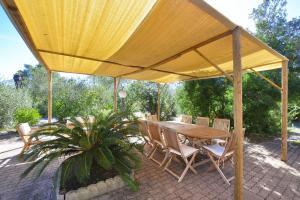 una mesa de madera y sillas bajo una sombrilla amarilla en Villino Saline - Happy Rentals, en Orbetello