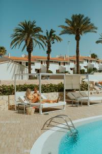 two people laying on lounge chairs next to a swimming pool at Olé Tropical Tenerife Adults Only in Playa de las Americas