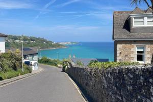 a house on the side of a road next to the ocean at The Lookout in Carbis Bay