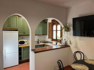 a kitchen with green cabinets and a white refrigerator at Mevak Home Alpujarra in Pórtugos +23 photos