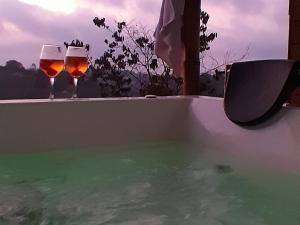 two glasses of wine sitting on the edge of a bath tub at Cabaña Starka & Jacuzzi in Marinilla