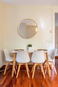 a dining room table with four white chairs and a mirror at Casabonita Santander in Santander