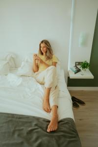 a woman sitting on a bed looking at her cell phone at Olé Tropical Tenerife Adults Only in Playa de las Americas +37 photos