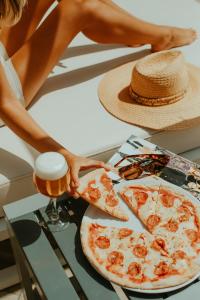 a woman holding a glass of beer next to a pizza at Olé Tropical Tenerife Adults Only in Playa de las Americas