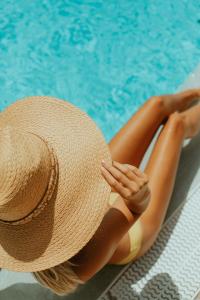 a woman in a straw hat sitting next to a swimming pool at Olé Tropical Tenerife Adults Only in Playa de las Americas