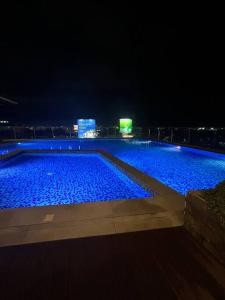 una gran piscina por la noche con luces azules en A cozy home feel with a city view - The Capitol at Sitari, en Bacolod