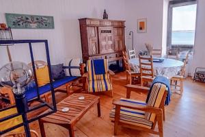 a living room filled with wooden chairs and a table at La Maison de la Plage - vue mer, 5' du port, 6 personnes in Île-Tudy