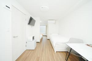 a white room with a bed and a desk at 東京リリアルホテル 301 in Tokyo