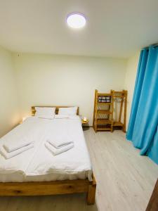 a bedroom with a bed with white sheets and a blue curtain at Dez Guest House, Margahovit, Lori in Margahovit +83 photos