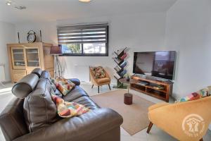 sala de estar con sofá de cuero y TV de pantalla plana en Villa armor azur, en Erquy