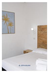 リド・ディ・オスティアにあるOstia Holiday Libertyのヤシの木の絵が飾られた白いベッドのある寝室 +24枚の写真