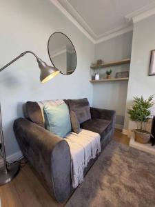 eine Ledercouch in einem Wohnzimmer mit einem Spiegel in der Unterkunft RNM - Business Contractors Ready! 3 Bedrooms, Efficient Savings! Entire House,Smart Tv, 2 Lounges, Dining Area, Private Gated Parking, Easy Access, Close to M5, Train Station, Bus Routes, Kitchen and Washroom plus amenities included! in Quinton