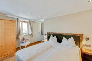 sypialnia z dużym białym łóżkiem i krzesłem w obiekcie Design Apartment Villa Anna Kitzbühel w mieście Kitzbühel +37 zdjęć