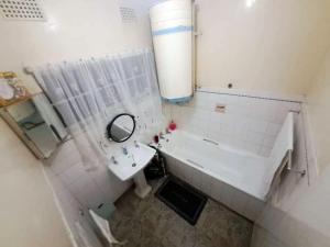 a bathroom with a sink and a tub and a mirror at The Adventure Begins in Bulawayo