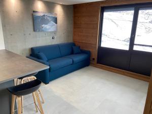 a blue couch in a room with a window at AltiPAM Lodge Val Thorens in Val Thorens