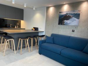 a living room with a blue couch and a kitchen at AltiPAM Lodge Val Thorens in Val Thorens