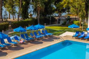 a pool with lounge chairs and blue umbrellas at Park Beach Hotel in Limassol