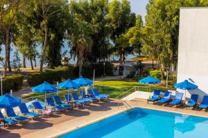 a swimming pool with chairs and blue umbrellas at Park Beach Hotel in Limassol