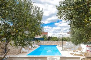 a pool with chairs and an umbrella and trees at House Anna in Drage