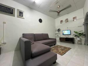 a living room with a couch and a tv at Zulaika Homestay in Kampung Gurun