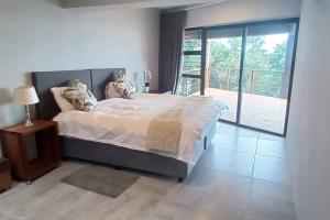 a bedroom with a large bed and a balcony at Cormorants' View Self Catering accommodation in Sedgefield