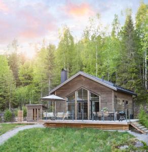 une cabane en rondins dans les bois avec une terrasse dans l'établissement Newly built cabin with sauna, fireplace and amazing view, à Järvsö