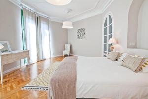 a white bedroom with a large bed and a desk at Friendly Rentals Caliu in Barcelona
