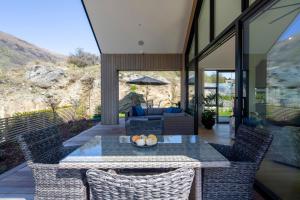a patio with a table and chairs and a couch at Beautiful Haven - Stunning Luxury Home - Queenstown - NEW!! in Queenstown