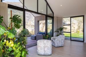 a living room with two chairs and some plants at Beautiful Haven - Stunning Luxury Home - Queenstown - NEW!! in Queenstown