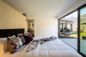 a bedroom with a bed and a large window at Beautiful Haven - Stunning Luxury Home - Queenstown - NEW!! in Queenstown