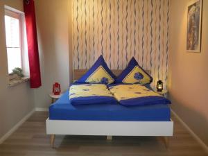 a bed with blue and yellow pillows on it at Haus Veronika in Fehmarn