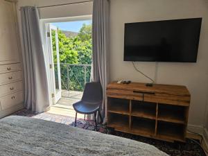 ein Schlafzimmer mit Fernseher und Kommode mit Stuhl in der Unterkunft PinotageLuxuryCollection 9A Herte Suite in Stellenbosch