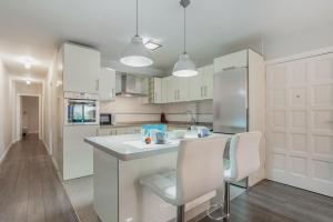 a kitchen with white cabinets and a counter and two chairs at Relax Playa San Telmo in Puerto de la Cruz