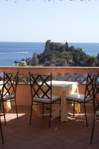 a table and chairs on a balcony with the ocean at Mendolia Beach Hotel in Taormina