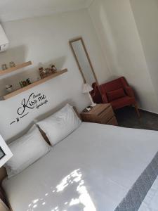 a bedroom with a white bed and a red chair at Margarita's House 2 in Kavála
