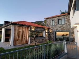 ein Haus mit einem Zaun und einem Haus in der Unterkunft Vila Rouxinol in Arco da Calheta