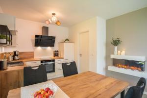a kitchen with a dining table and a fireplace at Fewo Lüttje Parl in Hooksiel +11 photos