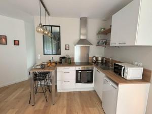a kitchen with white cabinets and a table with a microwave at Studio Titanic Cherbourg Parking in Cherbourg en Cotentin +10 photos