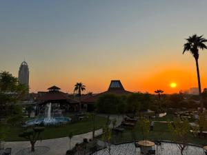 a sunset over a park with a fountain and a building at Erbil International Hotel in Erbil