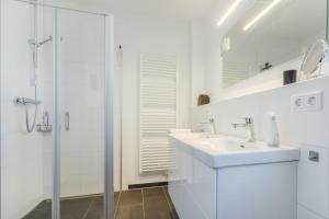 a white bathroom with a sink and a shower at Fewo Hygge Penthouse in Hooksiel