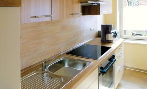 Una cocina con fregadero de acero inoxidable y gabinetes de madera. en Ferienwohnung Klabautermann, en Hooksiel