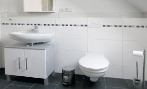 Un baño blanco con inodoro y lavabo. en Ferienwohnung Klabautermann, en Hooksiel