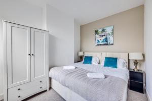 a bedroom with a large white bed with blue pillows at Charming House in Prime Location - Sleeps 7 - Free Parking, Fast WiFi, Smart TV with Netflix and Virgin TV by Yoko Property in Northampton