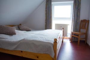ein Schlafzimmer mit einem Bett und einem Stuhl und einem Fenster in der Unterkunft Ferienwohnung Saalfeld in Schillig + 5 Fotos